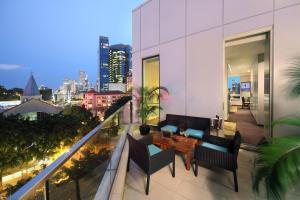 新加坡Park Regis Singapore的大楼内的阳台配有桌椅