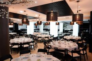 本讷图萨贝内图瑟酒店的餐厅设有白色的桌椅和吊灯。