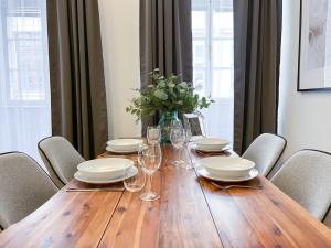 布拉格Best Price & Location - Historic Square Residency的一张木桌,配有椅子和盘子,酒杯