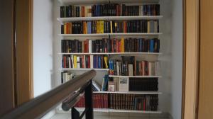 洛迦诺Casa Diana Locarno-Cugnasco的书架上书架,书架上摆放着楼梯旁的书籍