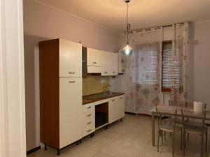 特拉莫Casa Barnabei 26的厨房配有白色橱柜、桌子和用餐室。