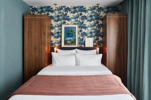 巴黎泰勒酒店的一间卧室配有一张带蓝色壁纸的大床