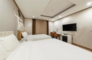 西归浦市Rex Hotel的酒店客房设有两张床和电视。
