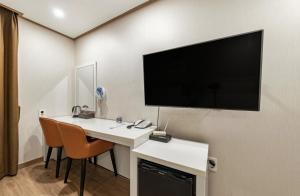 西归浦市Rex Hotel的客房设有一张桌子,墙上配有平面电视