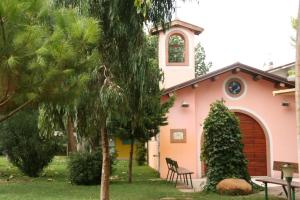 托尔托雷托Villaggio Welcome Riviera d'Abruzzo的粉红色的房子,前面有树和椅子