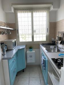 丽都迪奥斯蒂亚Holiday Gels appartamento vacanze Ostia的蓝色的厨房配有水槽和微波炉
