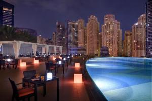 迪拜Address Marina Mall Suites "Full Marina Views & Balcony "的一个带桌椅的游泳池,享有城市天际线