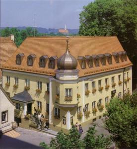 阿尔特廷阿尔施塔特舍科斯酒店的一座大型建筑,有瓷砖屋顶,外面的人站在