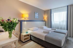 克莱佩达Aurora Hotel Klaipeda的配有床、桌子和鲜花的酒店客房