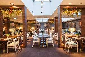 里加塔林酒店的配有木桌和白色椅子的餐厅