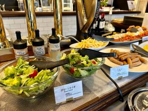 京都Henn na Hotel Kyoto Hachijoguchi的自助餐,包括一碗沙拉和瓶装葡萄酒
