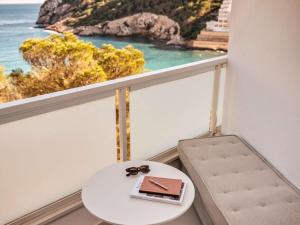 卡拉隆加Mondrian Ibiza的阳台上的桌子上放着书和眼镜