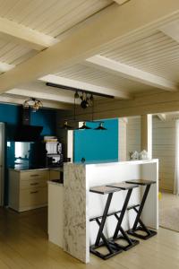 KrasnikВілла у горах的厨房设有蓝色的墙壁和带凳子的白色柜台。