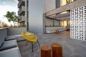 佩洛塔斯Studio contemporâneo no Parque Una com garagem的大楼里的一张黄色椅子和两张木凳