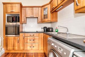 阿马Flat 4, 2 Victoria Street的厨房配有木制橱柜和洗碗机。