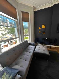 伦敦Stylish studio for 3 near Regent’s Park n3的客厅设有一张组合沙发和两个窗户
