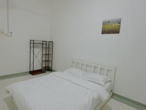 马六甲sling homestay的白色的房间里一张白色的床,墙上挂着一张照片