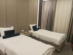 埃尔比勒达林广场酒店 的配有白色床单的酒店客房内的两张床