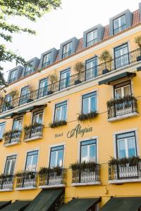 里斯本Alegria A Lisbon Boutique Hotel的黄色的建筑,设有窗户和阳台
