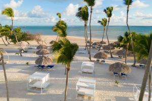 蓬塔卡纳Serenade Punta Cana Beach & Spa Resort的海滩上,有椅子和棕榈树,还有大海