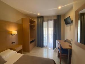 巴塞罗那坎东酒店的配有一张床、一张书桌和一扇窗户的酒店客房