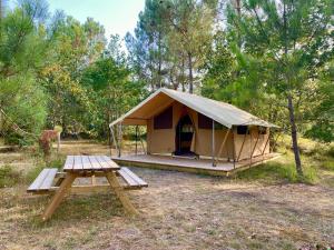 卡尔康Camping la Kahute, tente lodge au coeur de la forêt的帐篷前设有野餐桌