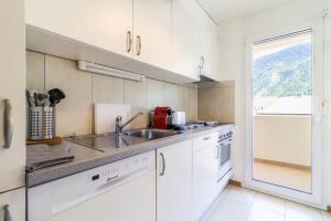 马蒂尼威尔Nice apartment ideally located in Martigny的厨房配有白色橱柜、水槽和窗户。