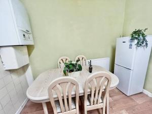 罗奇代尔Cosy 2 Bed House in Rochdale的厨房配有白色的桌椅和白色的冰箱。