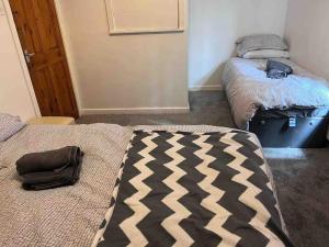 罗奇代尔Cosy 2 Bed House in Rochdale的一间设有两张床的客房,并在地板上备有一个袋子