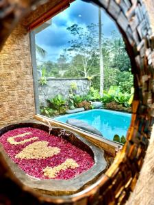 乌布PONDOK KUNGKANG VILLA 2的游泳池旁的浴缸里装满了粉红色的花朵