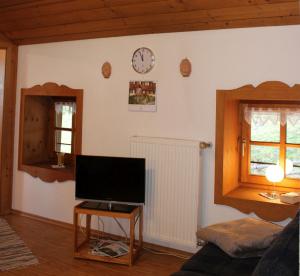 泰森多夫Bernerhof Ferienwohnungen Schmuck的客厅配有电视和墙上的时钟