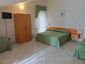 圣乔瓦尼·罗通多Hotel San Francesco的一间卧室配有一张床、一个橱柜和一台电视