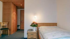 GontenHotel und Gasthaus Bad Gonten的一间卧室配有一张床和一张花瓶桌子