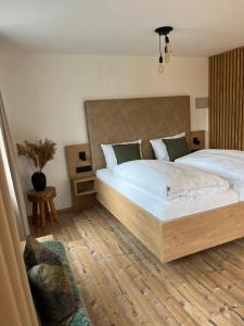 蒂蒂湖-新城MINAROSO appartements am badeparadies -ehemalig Kaltenbachs Appartements的一间卧室设有一张大床,铺有木地板