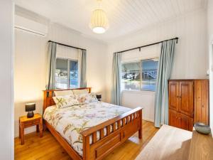 布里斯班Family friendly cozy 4BR house at Annerley的一间卧室设有一张床和两个窗户。