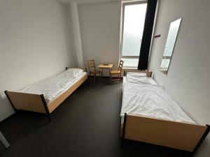 汉堡Arena Hostel & Monteurzimmer的配有两张床铺的客房配有桌椅