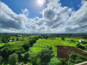 纳西克Trinity Stays Nashik - Mountain view apartment close to Sula的云天下田野的空中景观