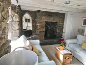 赫尔斯顿Samphire Cottage的带沙发和石制壁炉的客厅