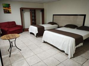 拉乔雷拉Hotel America - La Chorrera的酒店客房,设有两张床和一张红色椅子