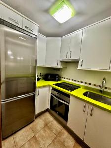 内尔哈Apartamento E&D的厨房配有白色橱柜和不锈钢冰箱