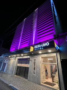 特奥菲卢奥托尼Hotel Beira Rio的站在建筑物外,有紫色灯的人