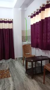 加雅Darbar Homestay的客厅配有紫色窗帘和桌子