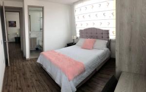 奇亚Hermoso apartamento con estacionamiento gratuito Chía N1的一间卧室配有带粉红色枕头的床和窗户。