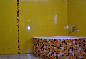 埃尔多雷特Zuri Guest House next to SOS & Kenmosa Village的黄色瓷砖浴室配有浴缸和水槽