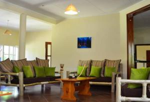 埃尔多雷特Zuri Guest House next to SOS & Kenmosa Village的客厅配有沙发和带绿色枕头的桌子