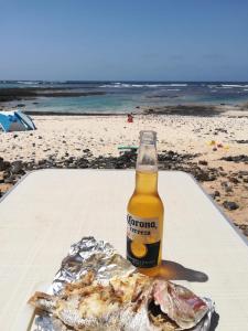 TetirFurgoCamper Van H1的海滩上的一瓶啤酒和一条鱼