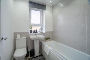 KnightswoodLocksley House的浴室配有白色浴缸、盥洗盆和卫生间。