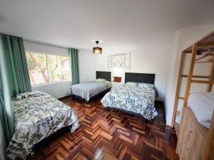 库斯科Casa Alpaca的一间卧室设有两张床,铺有木地板