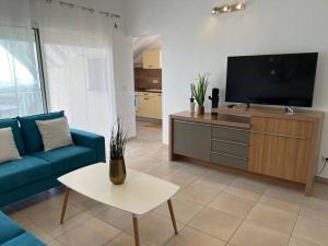 圣克洛德KANOA LODGE piscine et vue mer的客厅配有蓝色的沙发和平面电视。