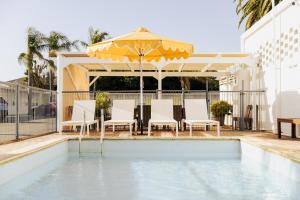 Port BroughtonPort Broughton Hotel and Sunnyside Motel的游泳池配有遮阳伞、椅子、桌子和遮阳伞